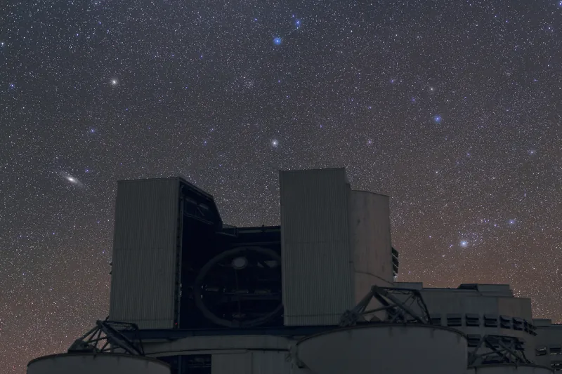 Ciel étoilé au-dessus d’une coupole du VLT, au Chili : la galaxie d’Andromède y forme une petite traînée claire