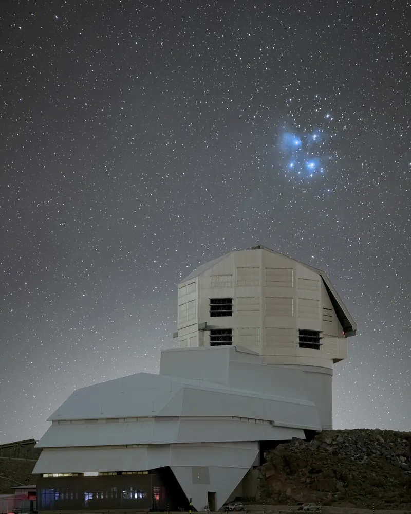 Les Pléiades, amas d’étoiles bleues voilé de nébulosité, brillent au-dessus du bâtiment de l’observatoire Rubin