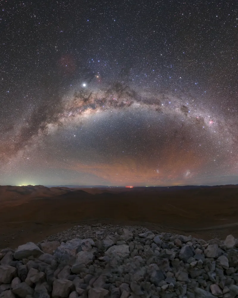 L’arche de la Voie lactée au-dessus d’un désert de pierres, sous un ciel semé d’étoiles