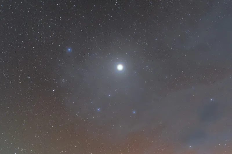 Jupiter, très brillante, entourée d’un halo, au-dessus du désert d’Atacama, sous un ciel étoilé aux lueurs rouges et vertes