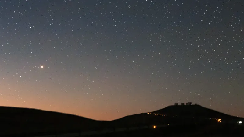 Mars, point rouge vif dans un ciel d’étoiles à l’aube, au-dessus de la colline de Paranal et des télescopes du VLT