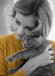 Jeune femme blonde serrant son chat gris contre elle