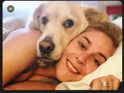 Jeune femme et son golden retriever blottis l’un contre l’autre au réveil