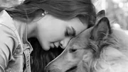 Femme posant sa joue contre la tête de son colley, photo en noir et blanc