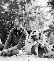Homme assis dans l’herbe avec son dalmatien, photo en noir et blanc