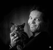 Homme souriant tenant un chat noir dans ses bras, portrait en noir et blanc