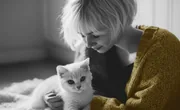 Femme penchée vers un chaton blanc, photo en noir et blanc