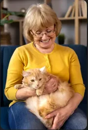 Femme âgée souriante tenant son chat roux sur ses genoux