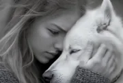 Jeune femme serrant tendrement un chien blanc contre sa joue, photo en noir et blanc