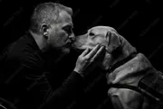 Homme embrassant son chien sur fond noir, photo en noir et blanc