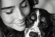 Femme souriante serrant son épagneul contre elle, photo en noir et blanc