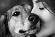 Femme blottie contre la tête de son chien, portrait en noir et blanc