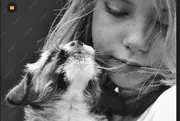 Jeune fille tenant un chiot contre son visage, photo en noir et blanc