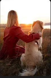 Jeune femme serrant son golden retriever face au coucher de soleil