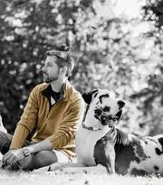 Homme assis dans l’herbe à côté de son dalmatien, photo en noir et blanc