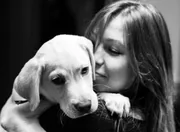 Jeune femme câlinant un chiot labrador, photo en noir et blanc