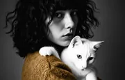 Femme aux cheveux bouclés serrant son chat blanc, portrait en noir et blanc