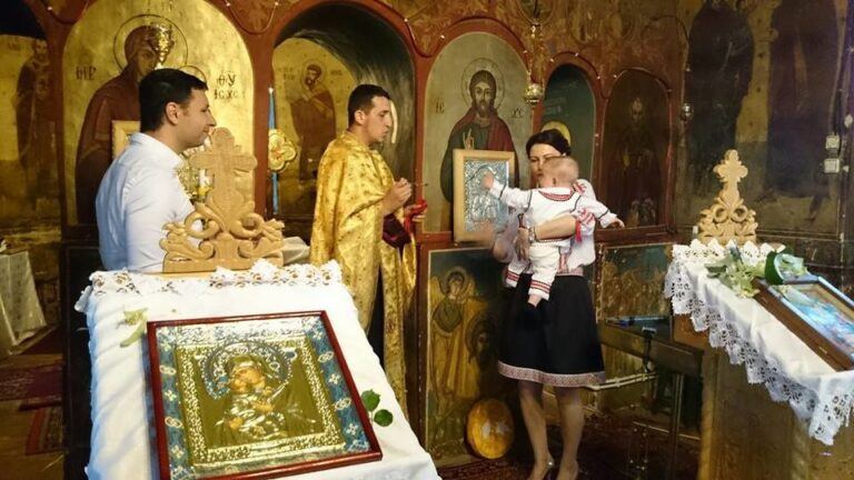 Prêtre orthodoxe célébrant le baptême d’un bébé devant les icônes