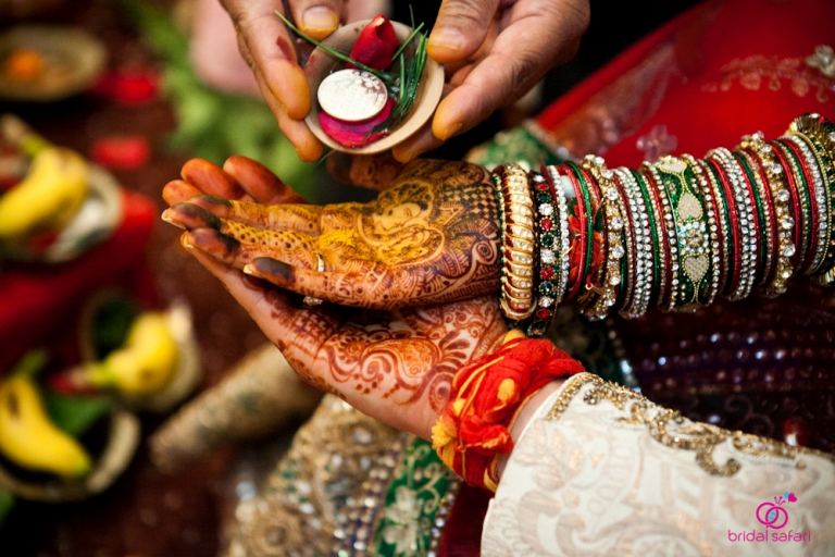 Mains d’une mariée indienne parées de henné et de bracelets